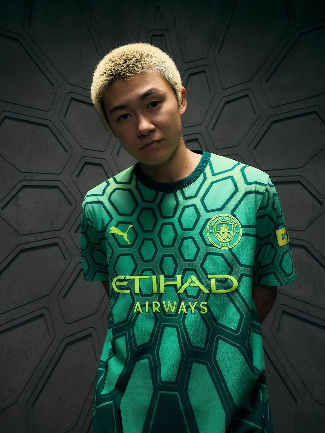 Yamashita wearing a green sports jersey with 'Etihad Airways' on a dark textured background