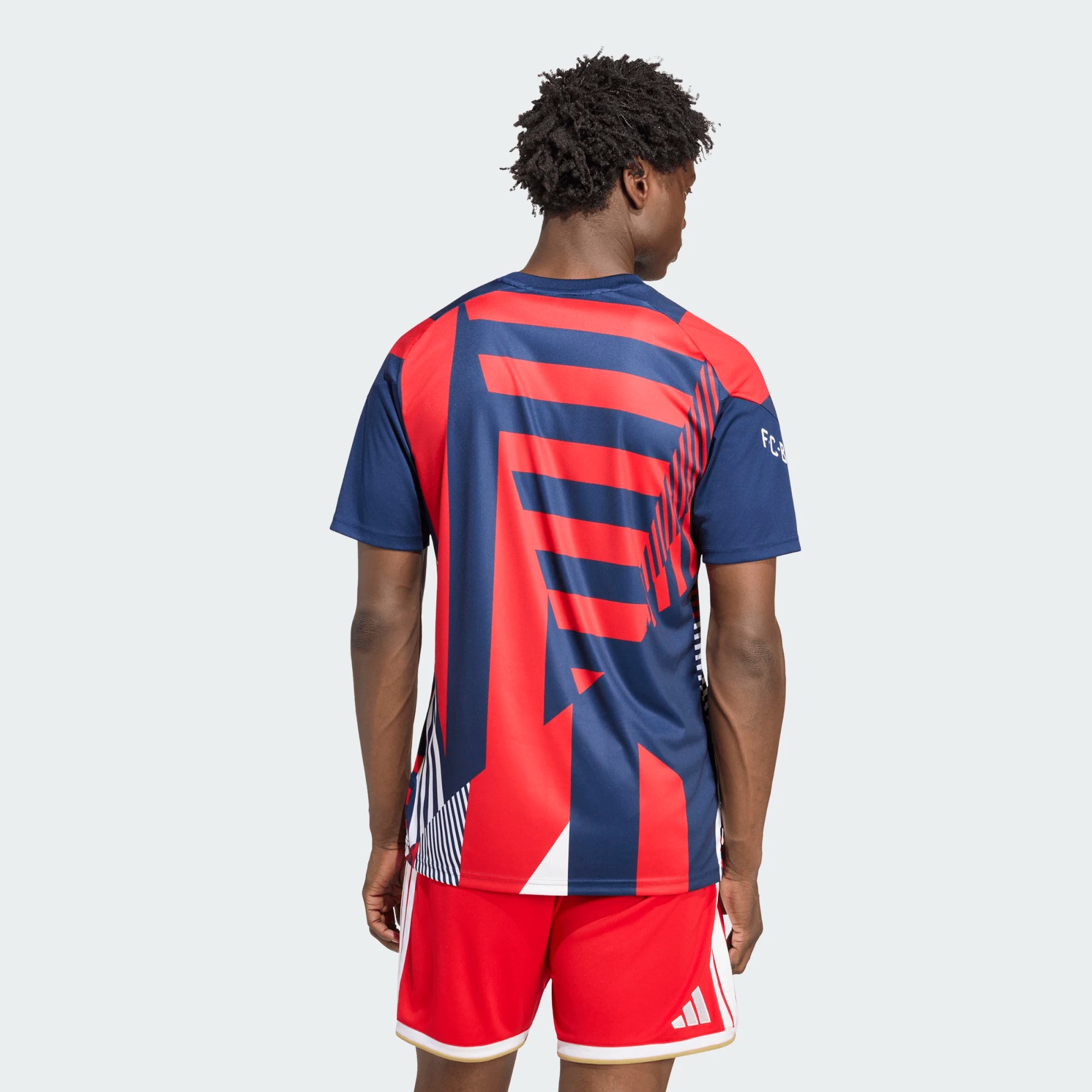 Person wearing a red and blue sports jersey with Adidas logo on a white background