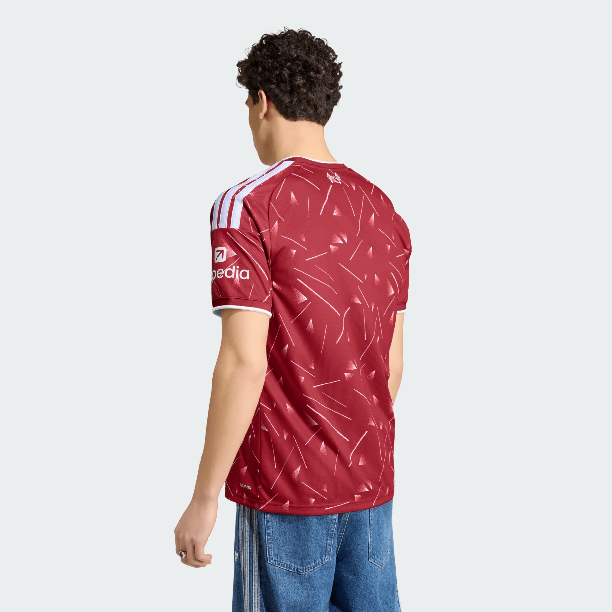 Person wearing a maroon sports jersey with a logo on the back, standing against a white background