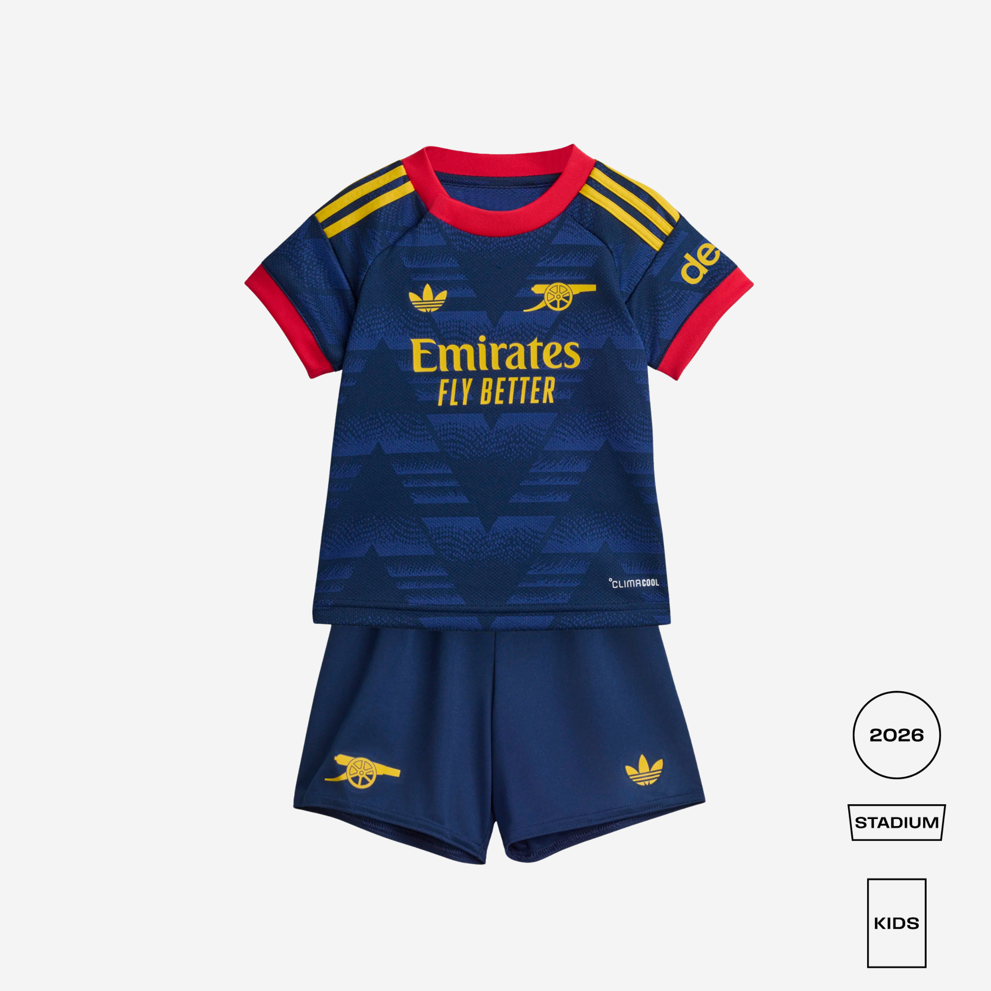 A kids' Arsenal football kit featuring a navy blue patterned jersey with red collar and sleeve cuffs, yellow stripes, and gold Adidas and Arsenal branding, paired with matching navy shorts with gold logos, shown on a light gray background with 2026 Stadium Kids labels.