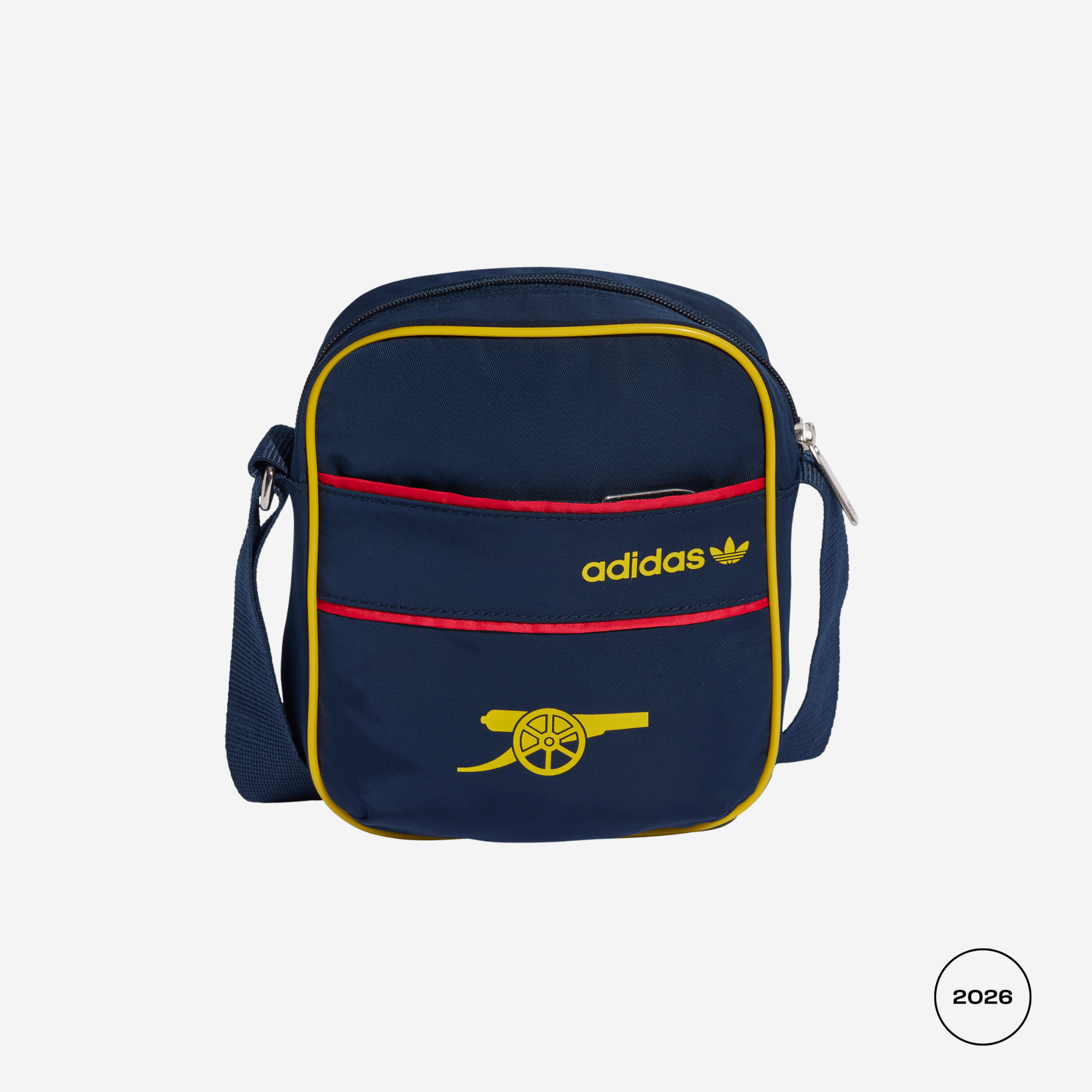 A navy blue Adidas crossbody bag with yellow and red accents, featuring the Adidas logo and a yellow cannon emblem on the front pocket, set against a light gray background.