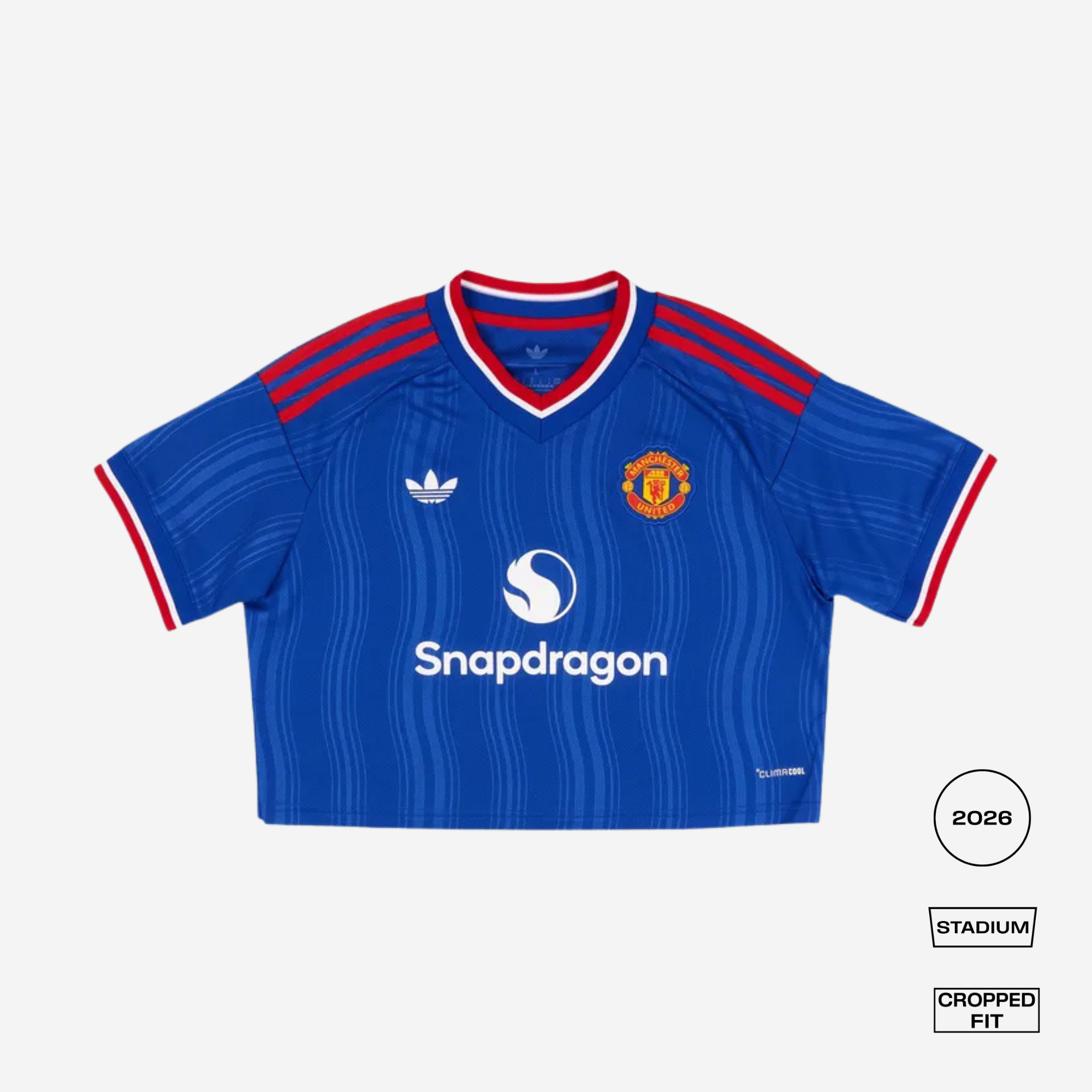 A cropped fit blue Manchester United football jersey with red and white trim, featuring the Adidas logo, Manchester United crest, and Snapdragon sponsor logo, shown on a light gray background with fit/style labels.