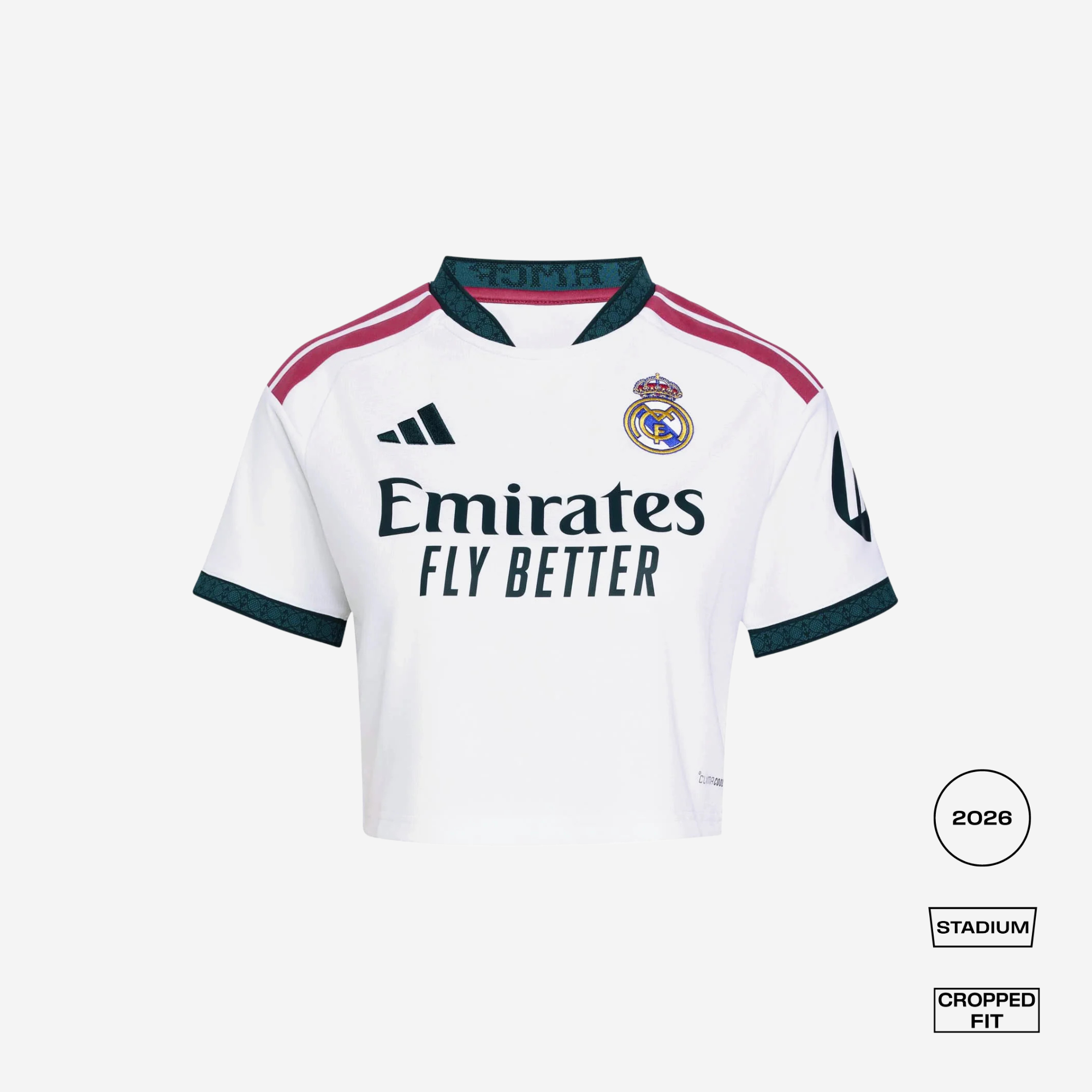 A white Real Madrid 2026 Stadium cropped fit jersey by adidas, featuring dark green and pink accents on the collar, shoulders, and cuffs, with the Emirates Fly Better sponsor logo on the front.
